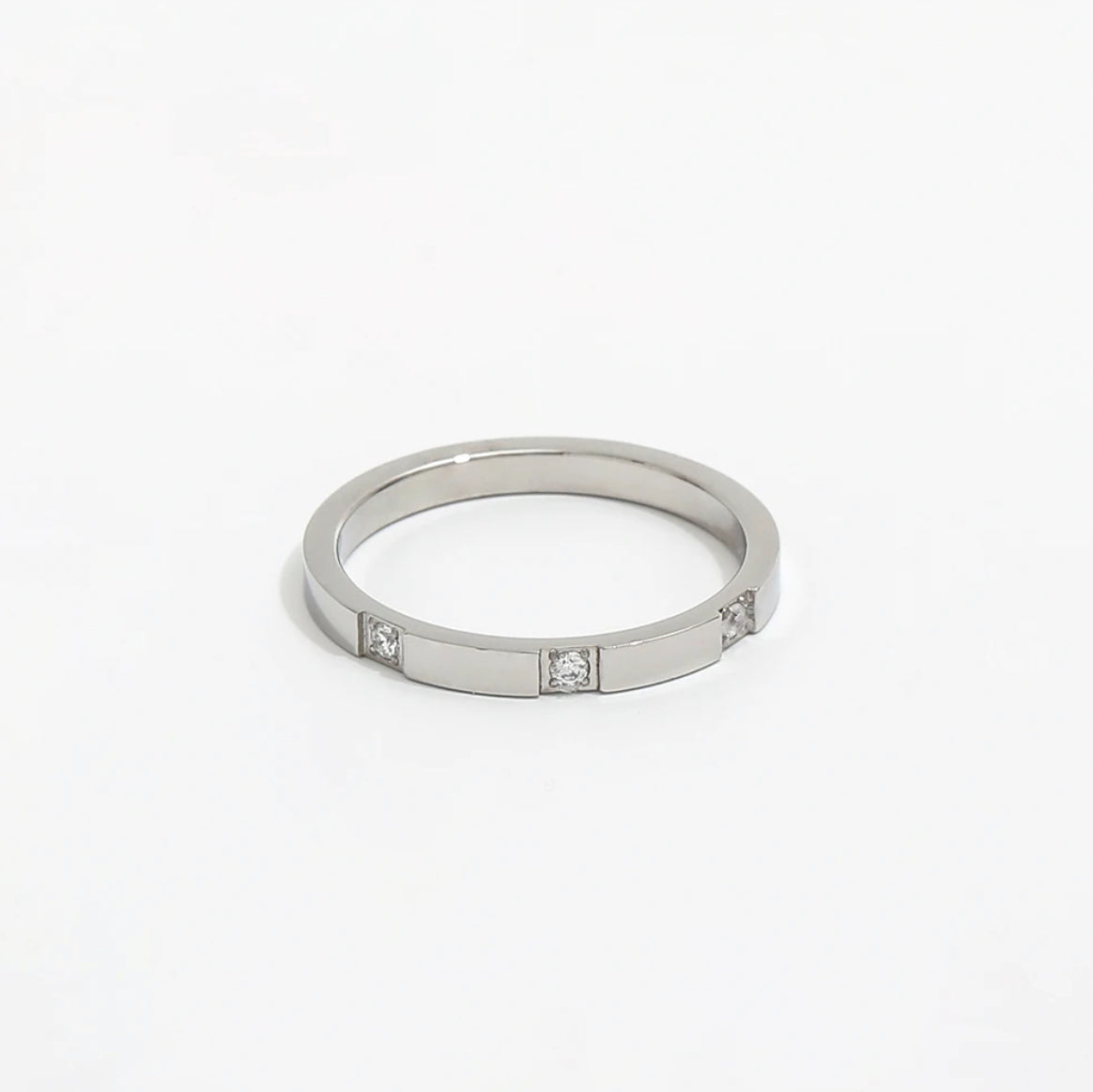 A silver band ring with three zirconia stones set in a gold band, with a polished finish.