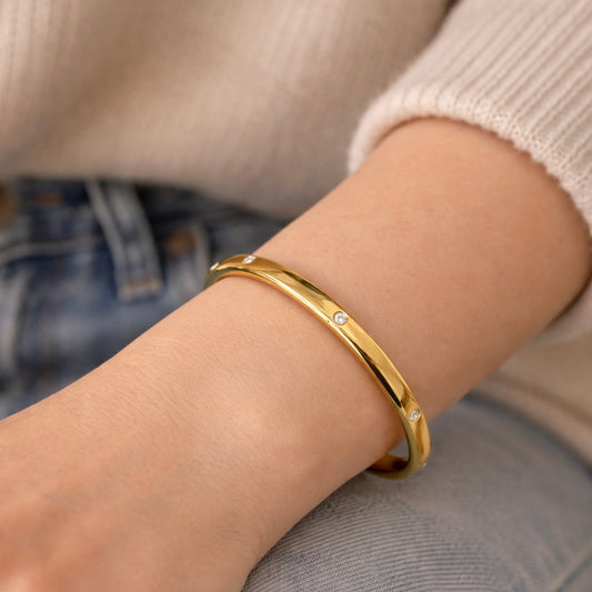 Gold bracelet on a person's wrist with a blurred background