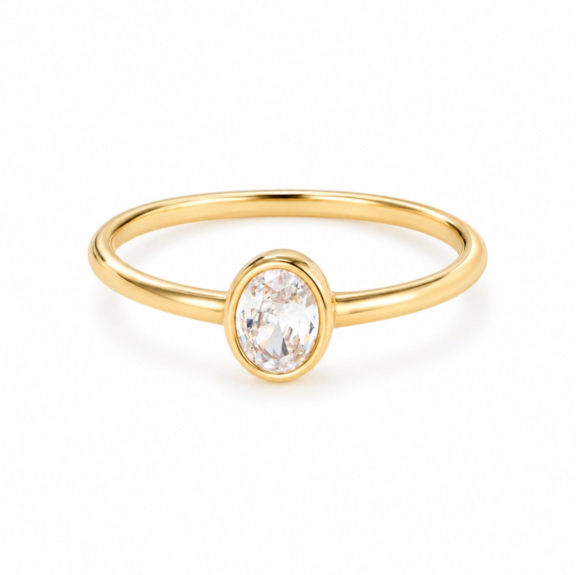 A delicate yellow gold ring featuring a bezel-set oval clear gemstone, shown on a clean white background.