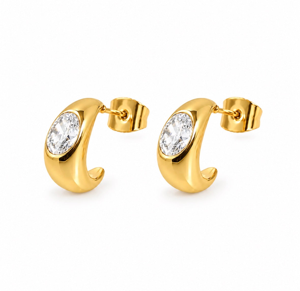 A pair of gold crescent-shaped hoop earrings with oval clear gemstones, shown on a plain white background.