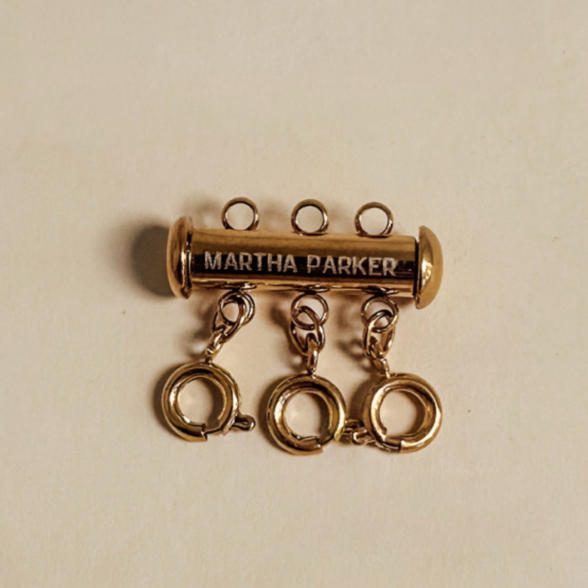 Gold charm with 'Martha Parker' engraving on a beige background
