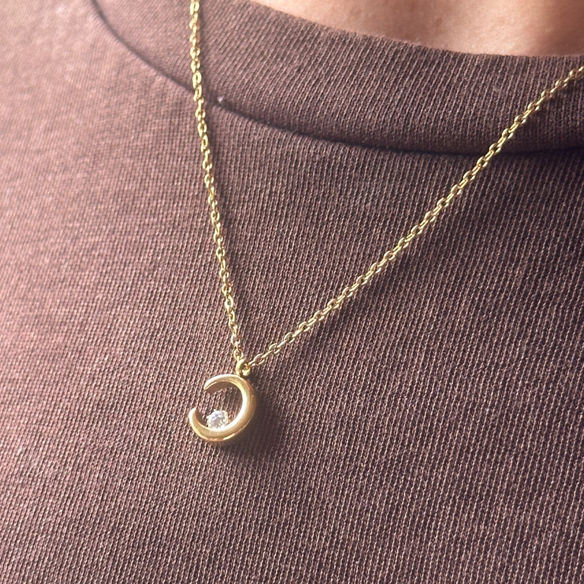Gold necklace with a crescent moon pendant worn on model