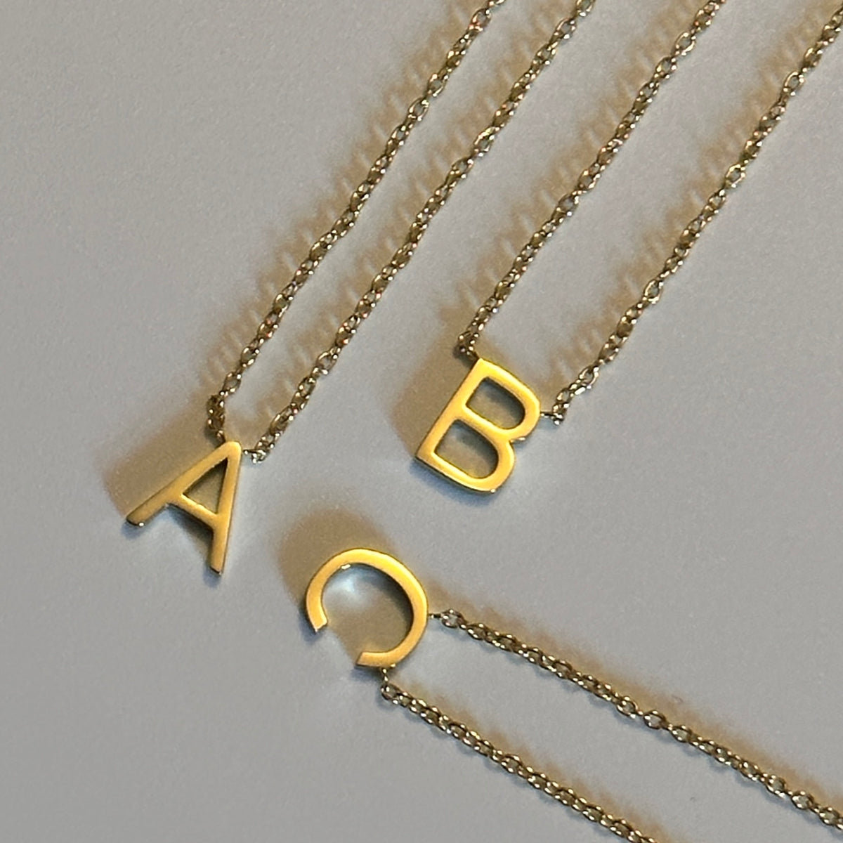 up close photo showing letter A B C initial necklaces