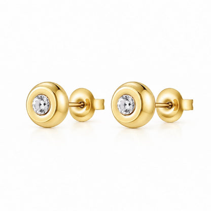 A pair of gold stud earrings with a circular bezel setting holding a clear round-cut gemstone, shown on a clean white background.
