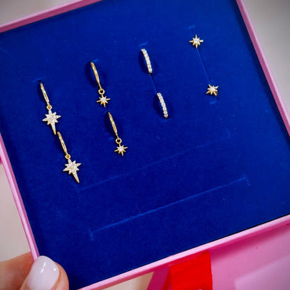 A collection of earrings including 1 set of north star drops, a smaller star drop, pave gold cz hoops and pair of star stud earring displayed in a giftbox.