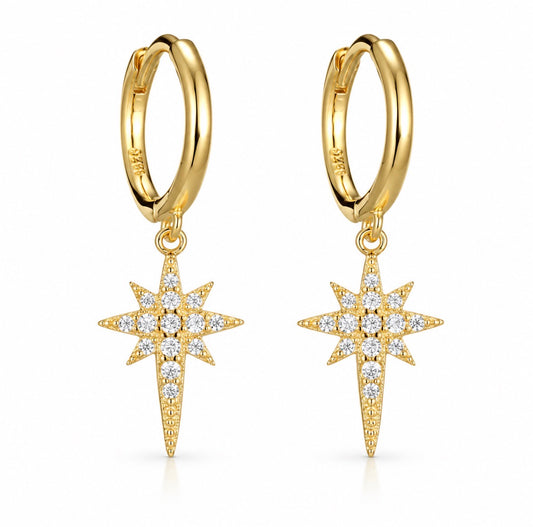 A pair of gold huggie hoop earrings with dangling starburst charms set with clear gemstones, shown on a clean white background.