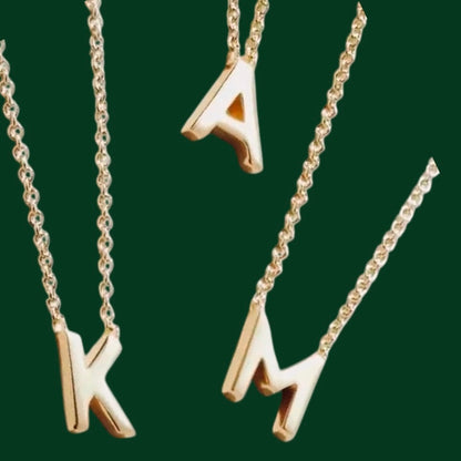 Gold necklaces with letter pendants on a green background