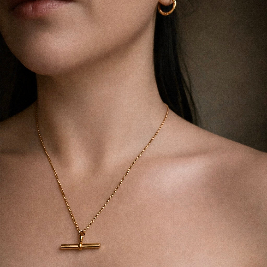 Gold rolo necklace with a T-Bar pendant on a person showing detail and length of chain  