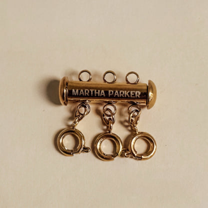 Gold charm with 'Martha Parker' engraving on a beige background