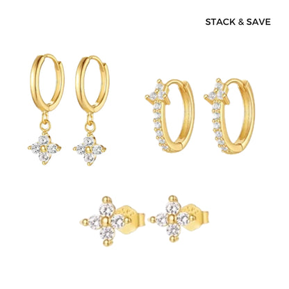 A collection of gold-colored earrings including drop hoop earrings, stud earrings, and clover earrings, displayed against a white background.