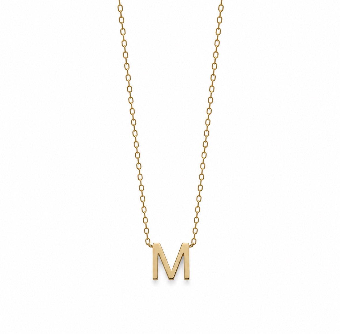 A delicate gold chain necklace featuring a polished gold capital letter 'M' pendant, shown against a plain white background.