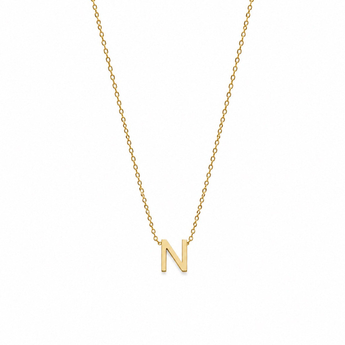 A delicate gold chain necklace featuring a small, polished gold initial pendant 'N' on a plain white background.