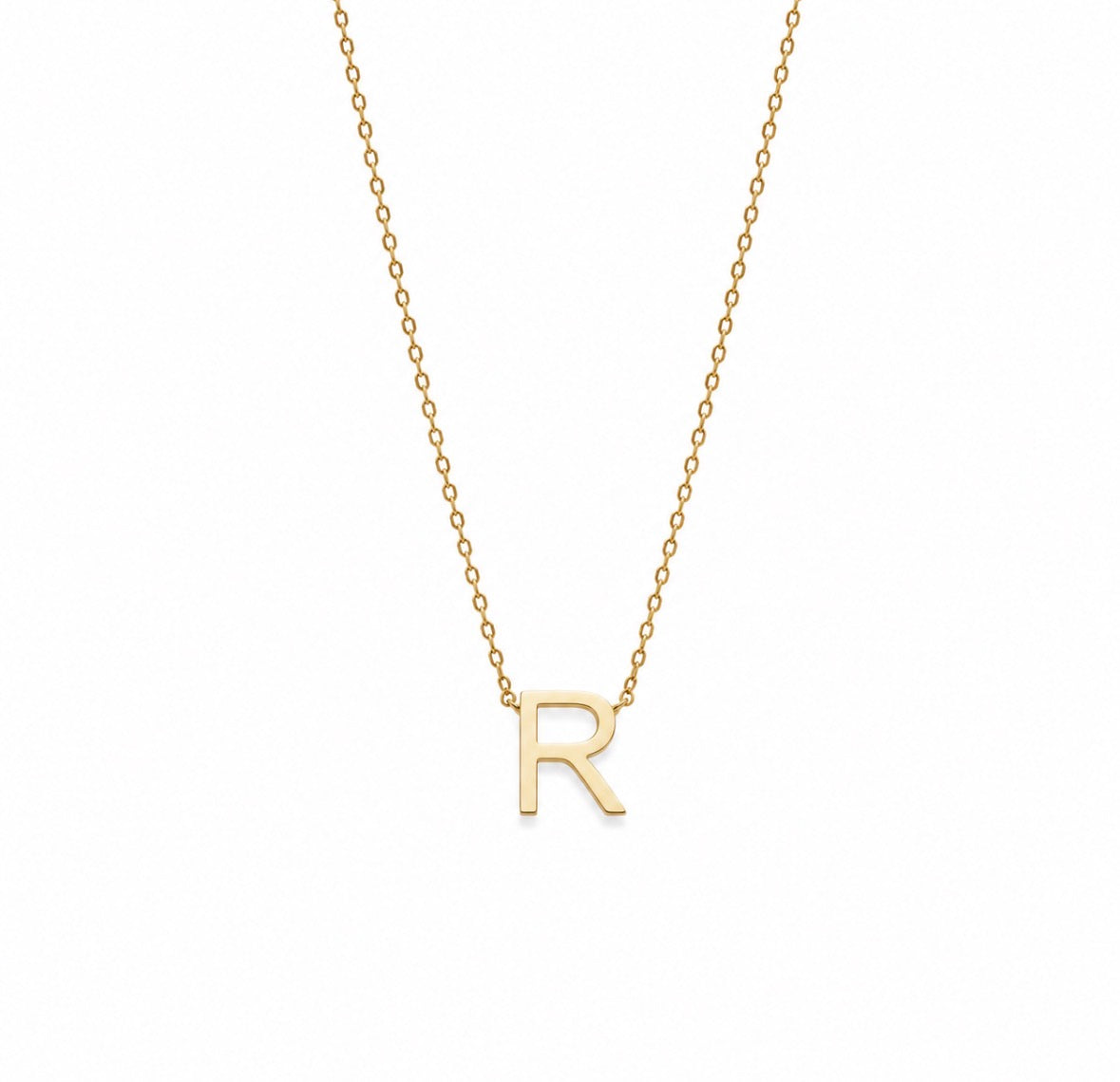 A delicate gold chain necklace featuring a polished gold initial pendant 'R', presented on a clean white background.
