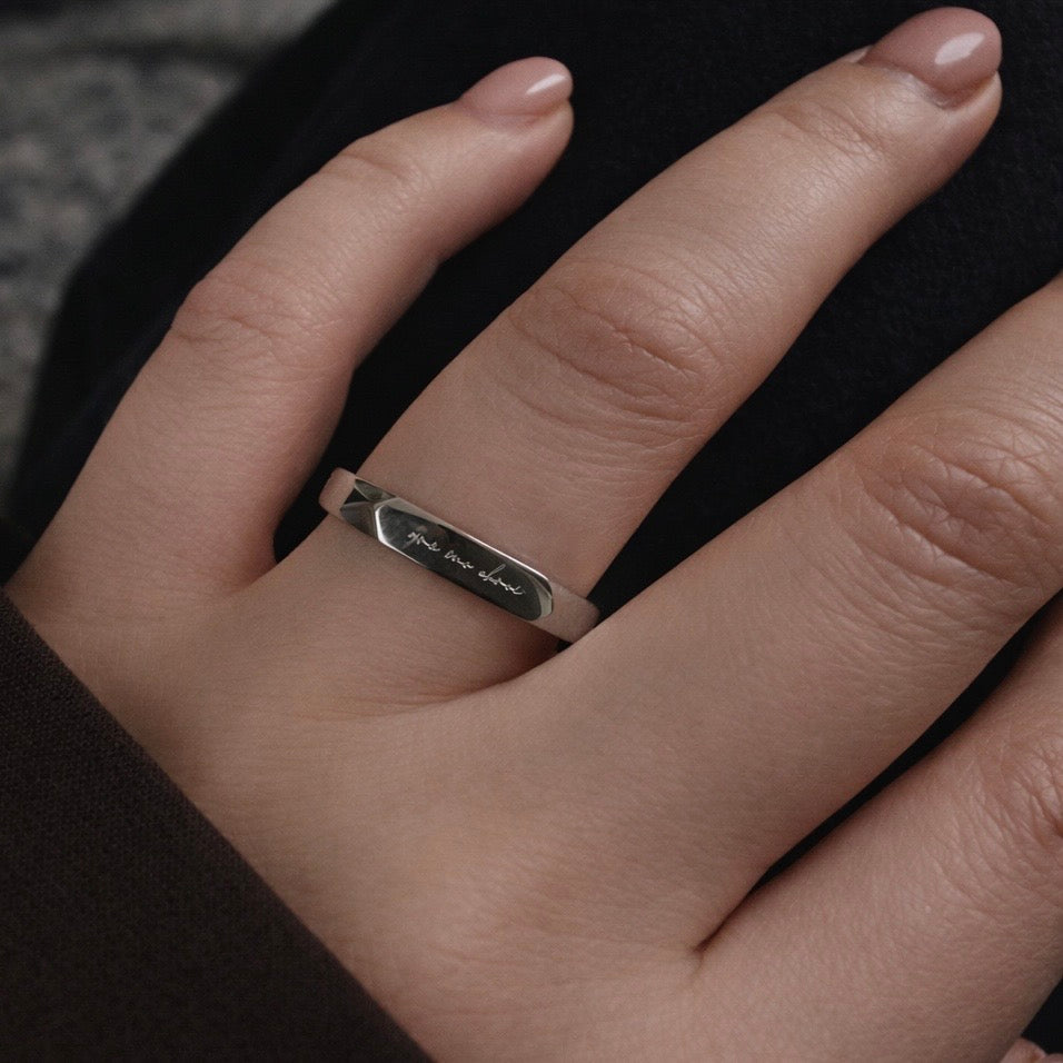 silver stainless steel ring with a light engraved Irish phrase grá mo chroí meaning love of my heart on a models finger 