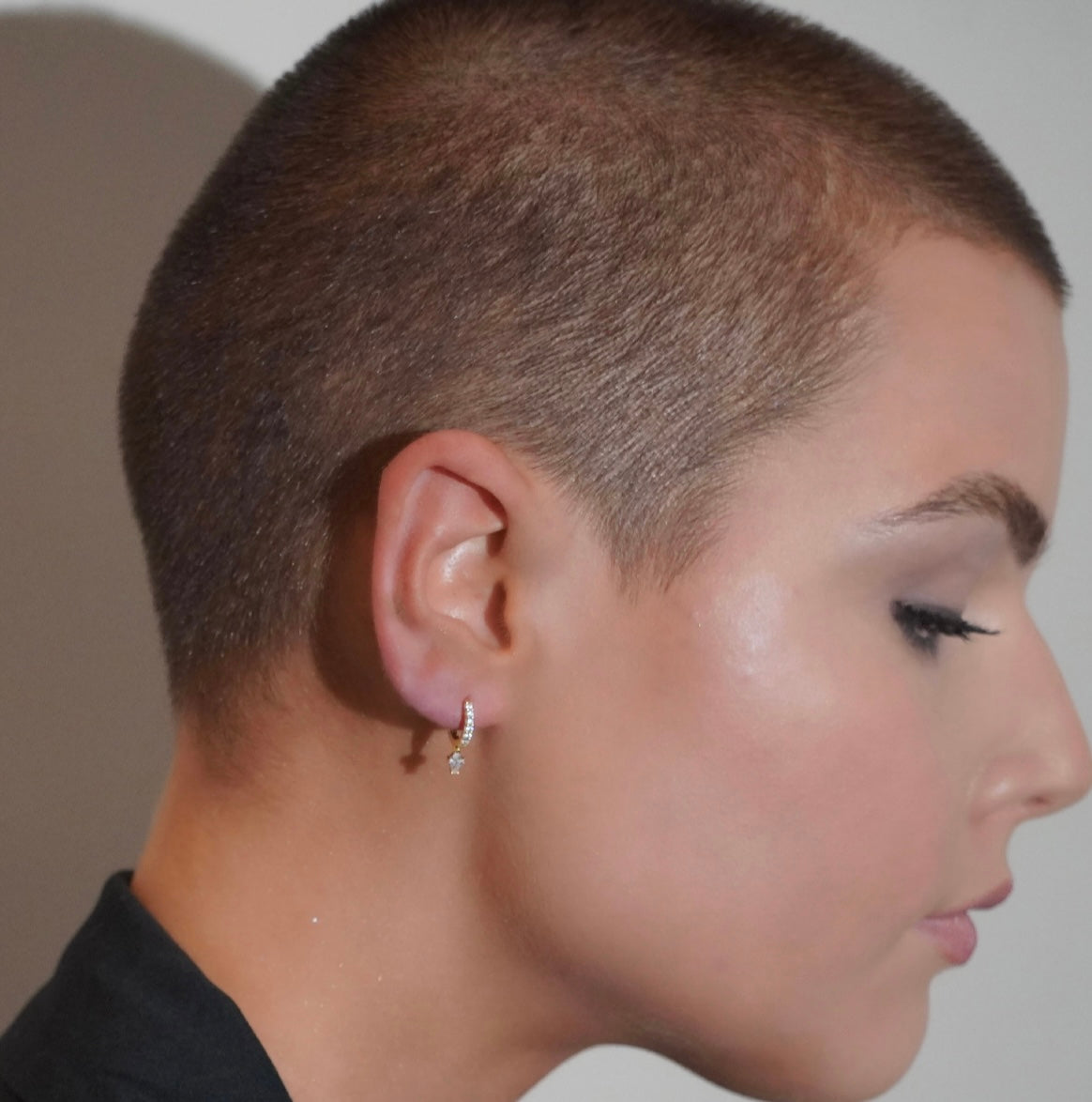 Side profile of a person with a shaved head wearing Cubic Zirconia Huggie Hoop