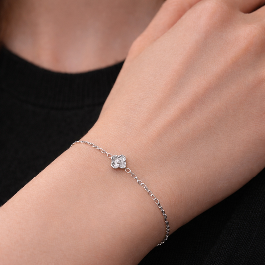  silver stainless steel clover chain bracelet on a models wrist. delicate chain with one mini clover motif in the centre. 