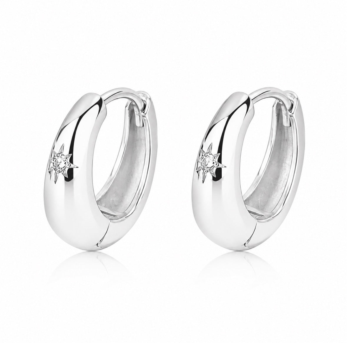 Pair of silver tapered hoop earrings with small star engraved star cubic Zirconia on a white background