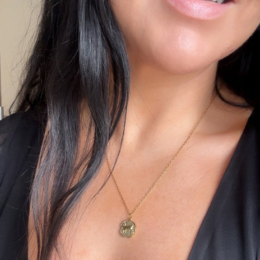 Close-up of a aries zodiac necklace with a pendant worn by a person
