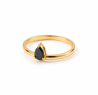 A gold ring featuring a teardrop-shaped black gemstone in a prong setting, photographed on a clean white background.