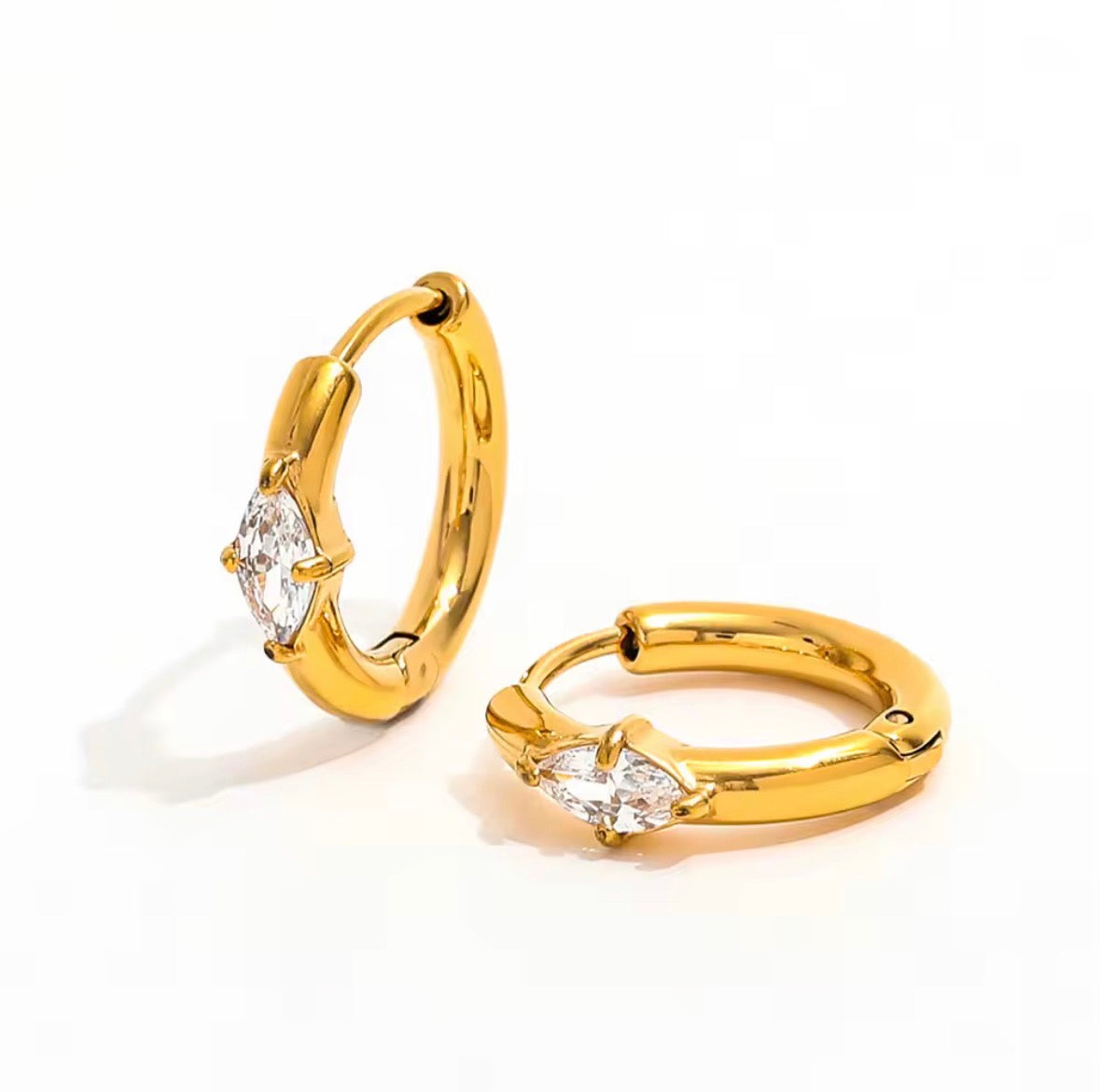 A pair of gold huggie hoop earrings with marquise-cut clear gemstones, displayed on a clean white background.