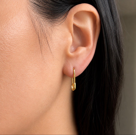 A close-up of a person's ear wearing a small gold hoop earring.