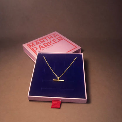 Gold necklace in a Martha Parker jewelry box on a brown surface