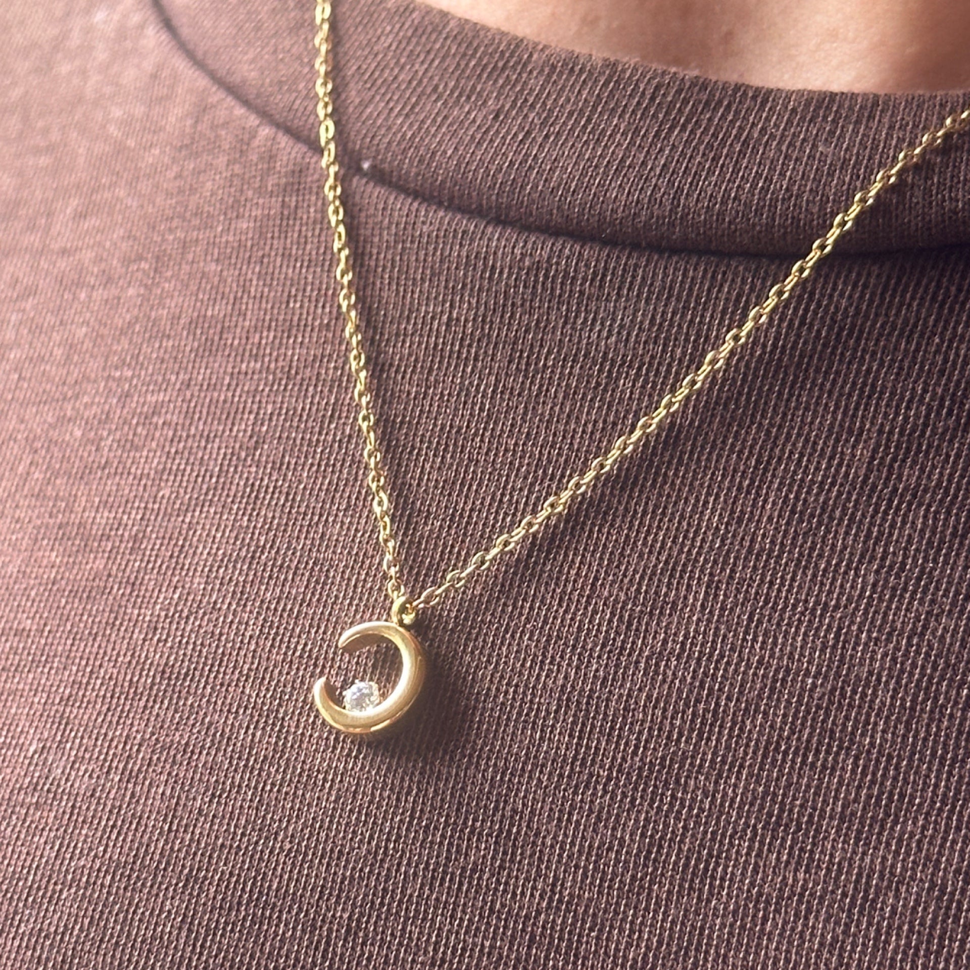 Gold necklace with a crescent moon pendant worn on model 