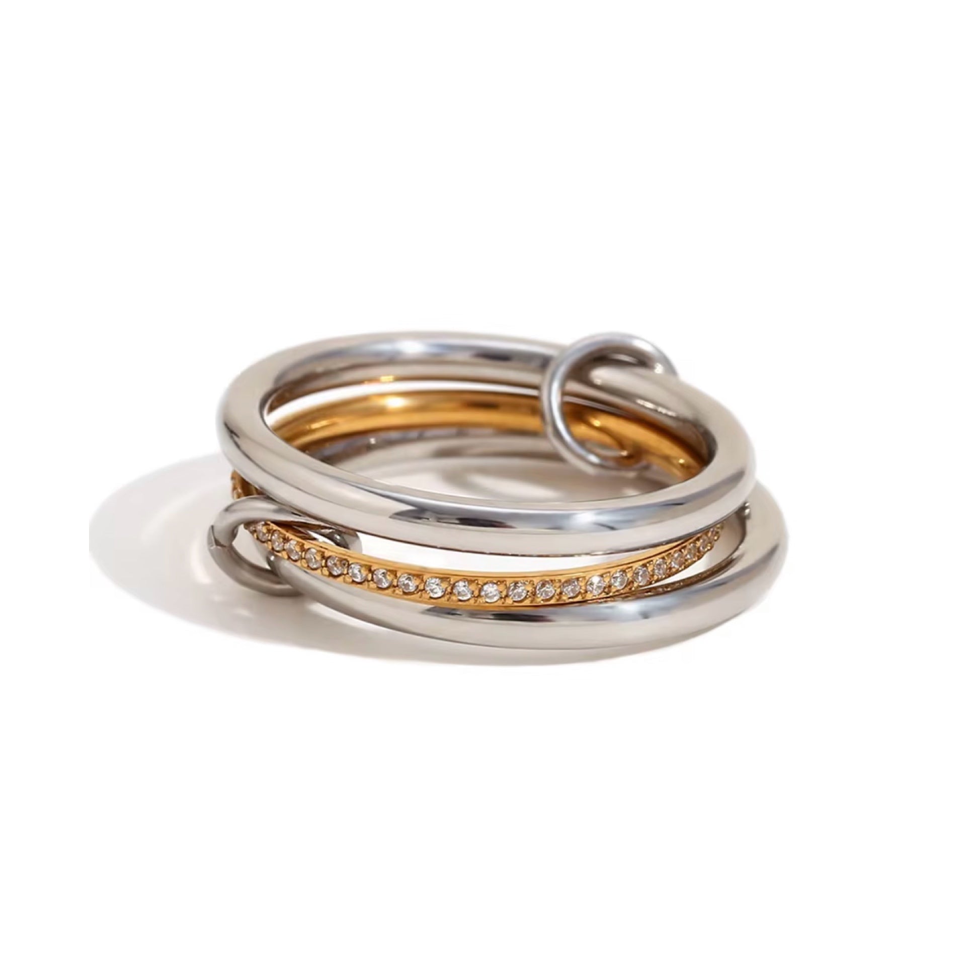 multi- link ring featuring three interconnected stainless steel bands. one gold band is adorned with pavé set stone to add a touch of sparkle, while the other two are plain silver polished bands. small metal loop connects the bands, enhancing the unique design. waterproof and tarnish free for lasting durability. 
