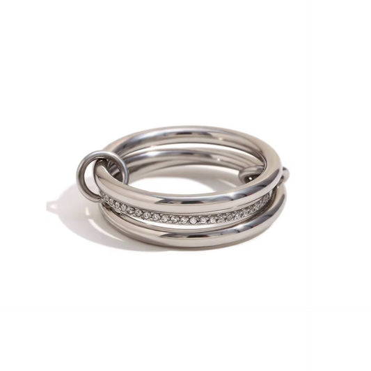 multi- link ring featuring three interconnected stainless steel bands. one band is adorned with pavé set stone to add a touch of sparkle, while the other two are plain polished bands. small metal loop connects the bands, enhancing the unique design. waterproof and tarnish free for lasting durability. 
