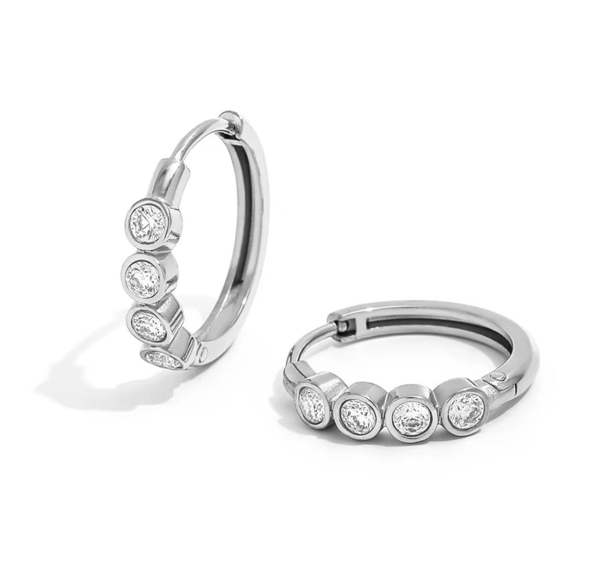 A pair of silver hoop earrings, each adorned with four round-cut clear gemstones in bezel settings, displayed on a clean white background.