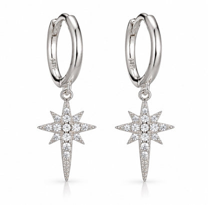 A pair of silver huggie hoop earrings with dangling starburst charms paved with clear stones, shown on a clean white background.