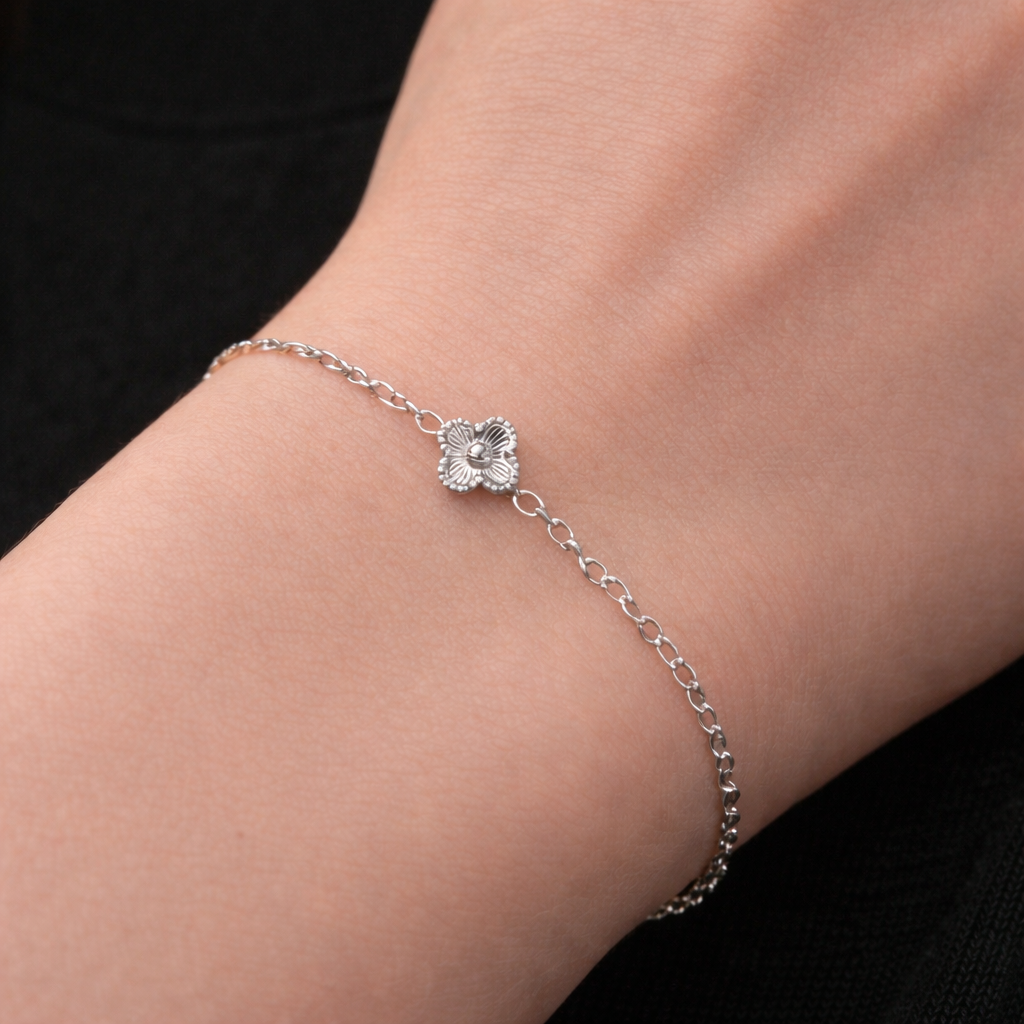 up close image of silver stainless steel clover chain bracelet. delicate chain with one mini clover motif in the centre. 
