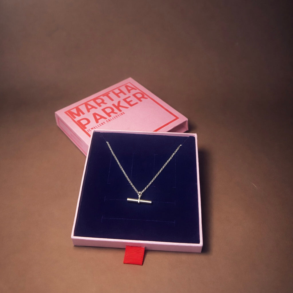 Silver necklace in a Martha Parker jewelry box on a brown background